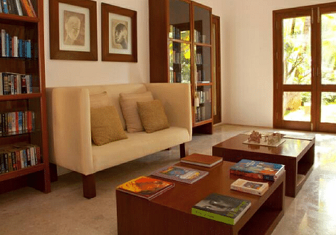A library with a couch, bookshelves, and artwork, indoor setting - Shreyas Retreat