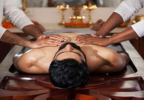 Two therapists performing a synchronized traditional full-body massage - Shreyas Retreat