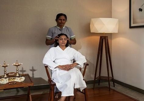 A client sitting comfortably while a therapist prepares for an Ayurvedic session - Shreyas Retreat