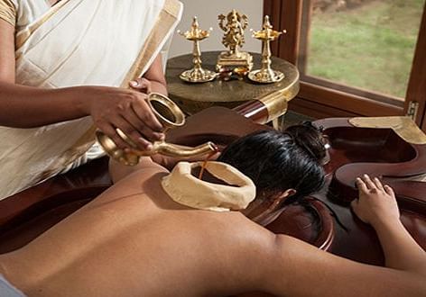 A therapist preparing herbal oils for a rejuvenating body massage - Shreyas Retreat