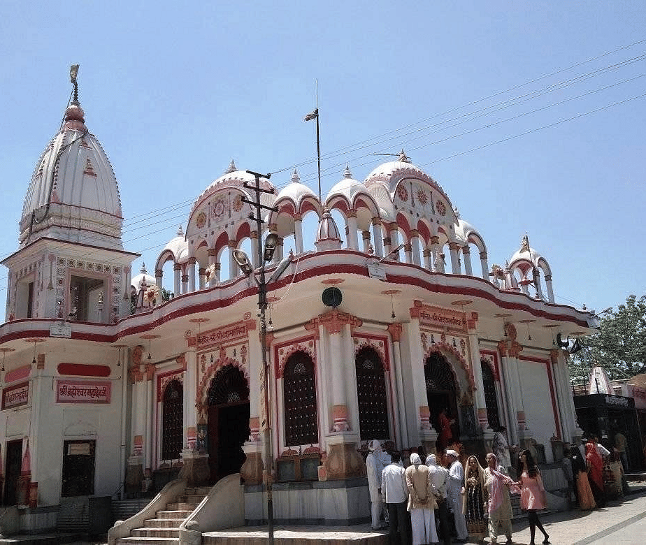 Visitors standing outside a temple with domes, arches, and traditional carvings during daytime