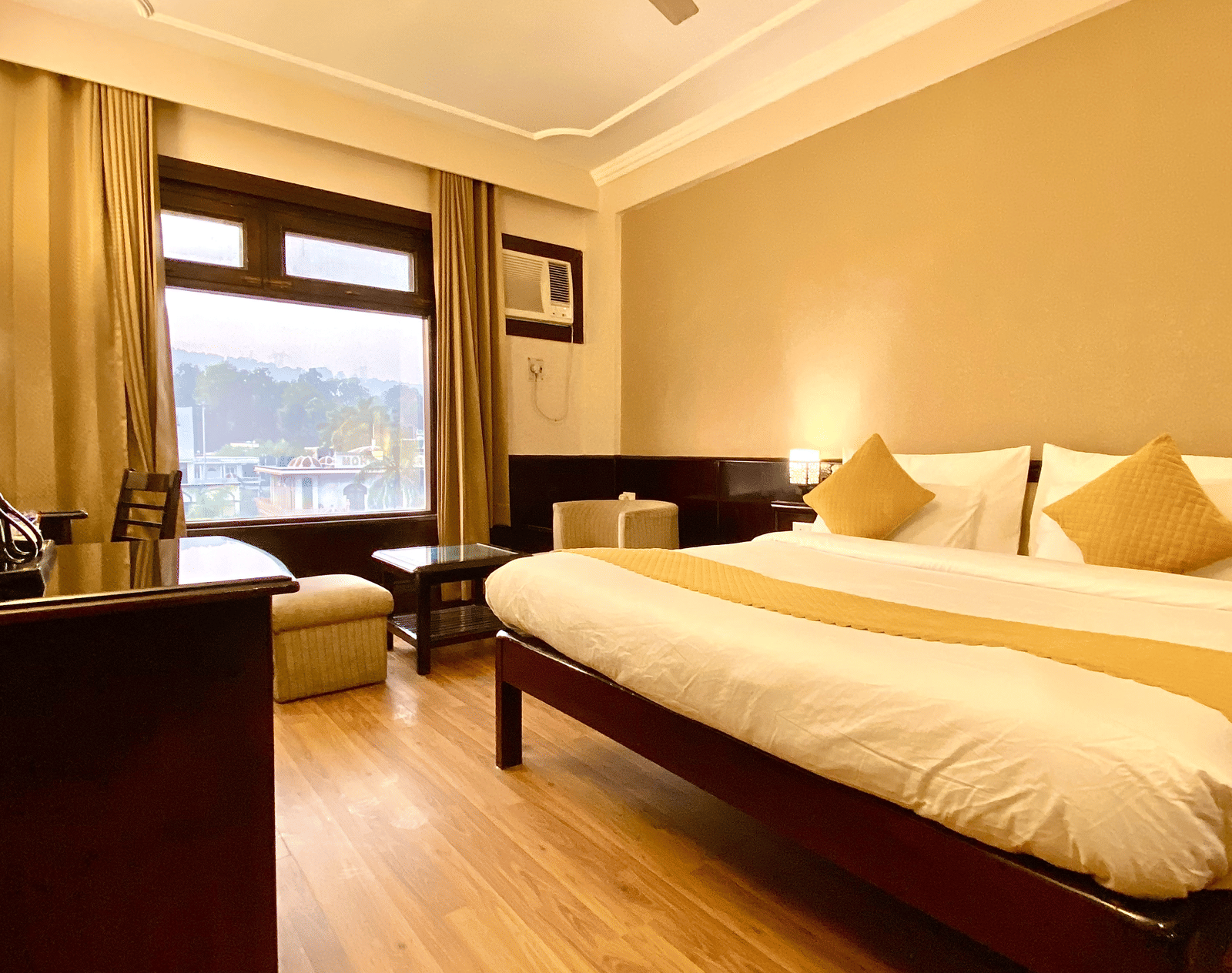 An overview of the Premium Room with a king size bed and multiple pillows at DLS Park Grace, Haridwar.