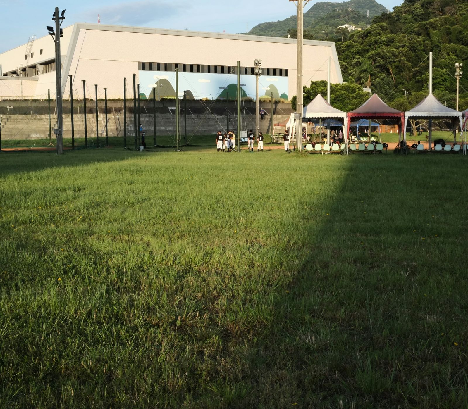A lawn with a large open space with tents a far.