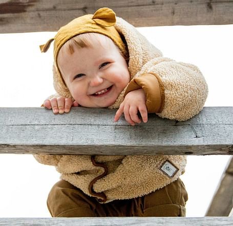 A baby wearing winter clothes smiling towards the camera