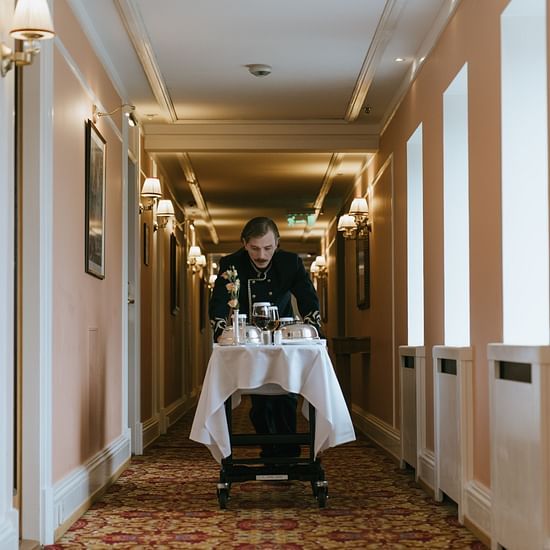 A waiter bringing something in the hallway of a hotel