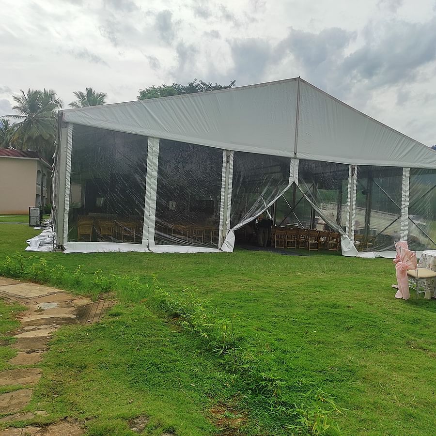 An outdoor tent structure set up on a grassy area with mountains in the background, possibly used for an outdoor event or wedding reception - Black Thunder, Coimbatore