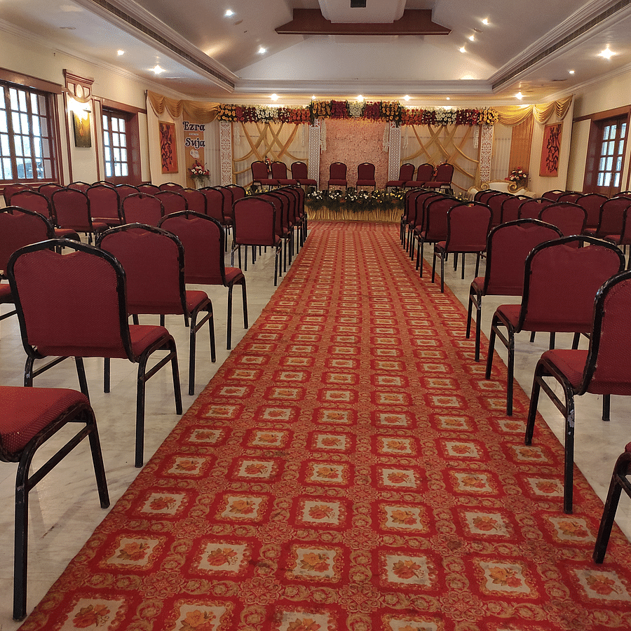 A view of an indoor conference or banquet hall with rows of red chairs lined up, ready for a formal meeting or event - Black Thunder, Coimbatore