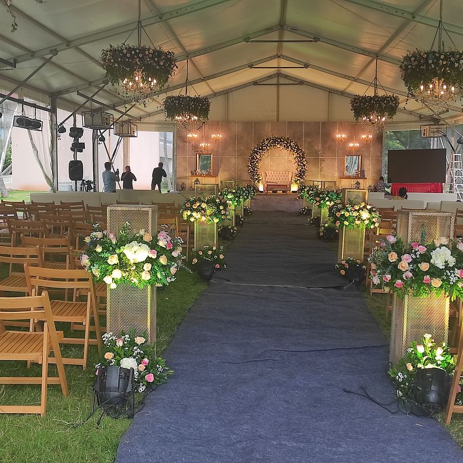 Outdoor wedding aisle with wooden chairs arranged on either side, leading to a decorated stage under a tent - Black Thunder, Coimbatore