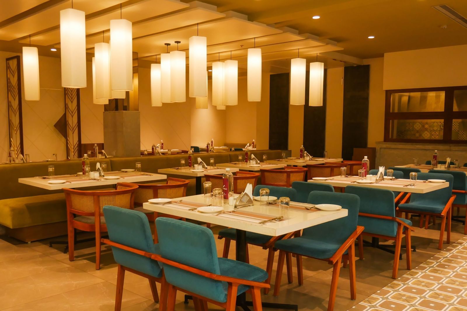 A brightly lit restaurant interior with tables set for dining and a buffet counter in the background at Shilton Dee Cee.