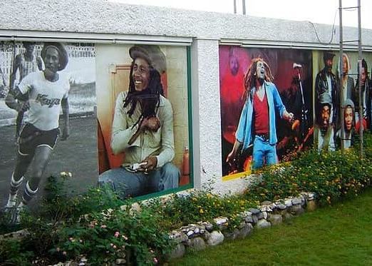 A long outdoor wall is adorned with colorful murals depicting various figures and scenes.