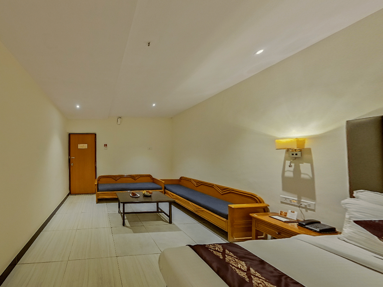 Spacious family room at Lords Eco Inn Dahej with L-shaped seating, coffee table, additional beds, and premium hospitality features