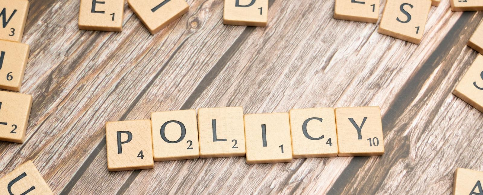 A wooden word puzzle featuring 'Policy' as the focal point