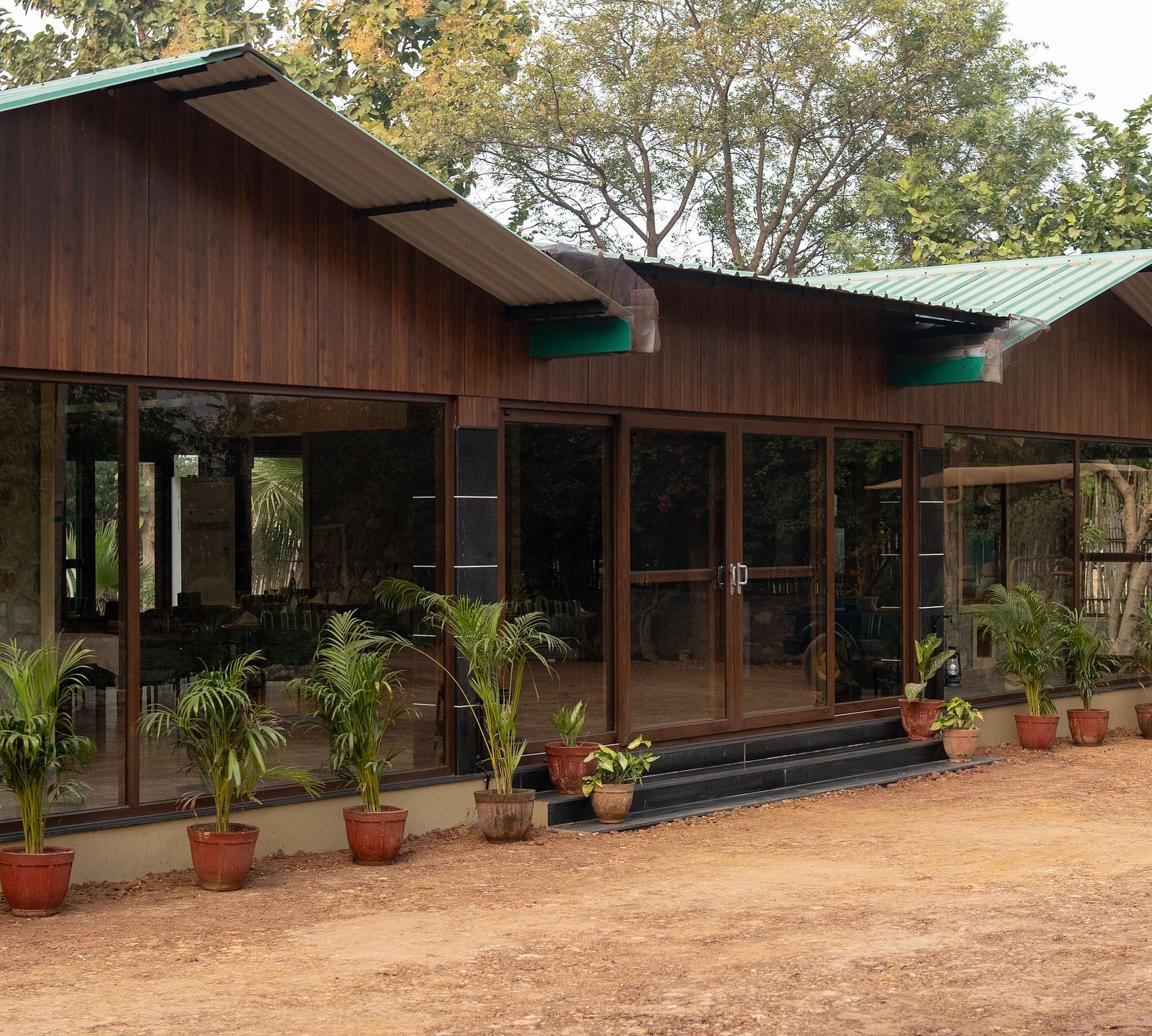 The charming main building of Aamaghati Jungle Retreat Ranthambore with a wide verandah and surrounding plants.