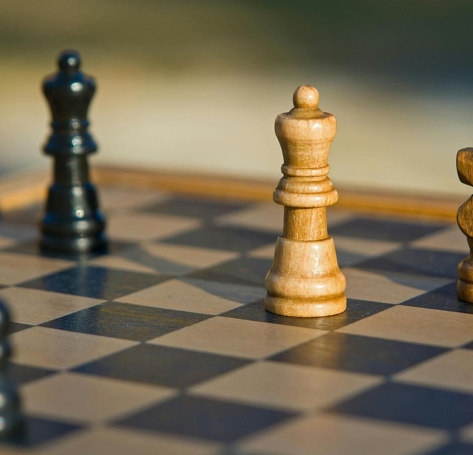 A wooden chess board with four chess pieces.