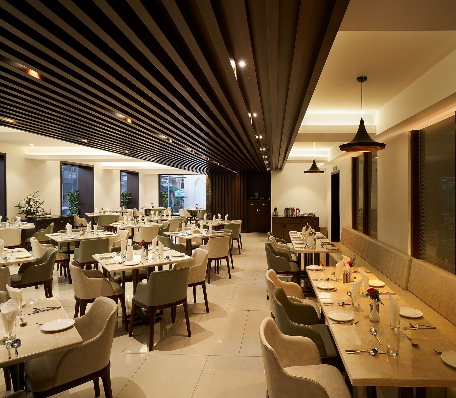 Spacious dining area with tables and chairs on one side, and seats along the wall on the other at The Hamuse Hotel, Kodaikanal.