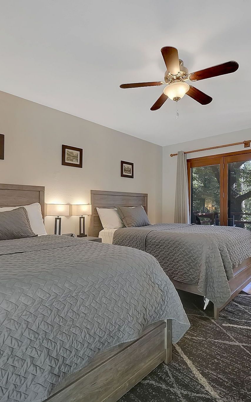 A view of a room at Narrow Gauge Inn with twin beds and sliding doors opening to a balcony.