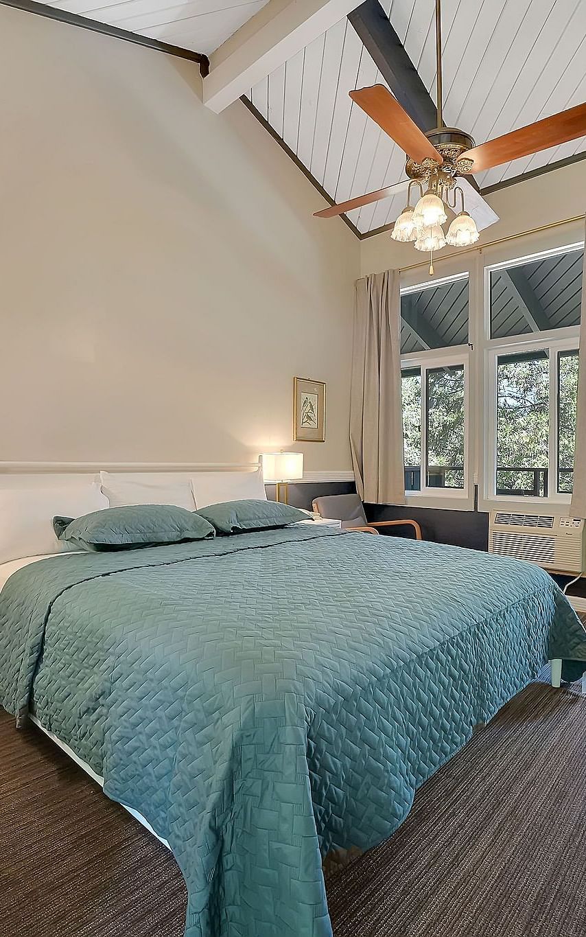 A view of a room at Narrow Gauge Inn with a double bed and sliding doors opening to a balcony.