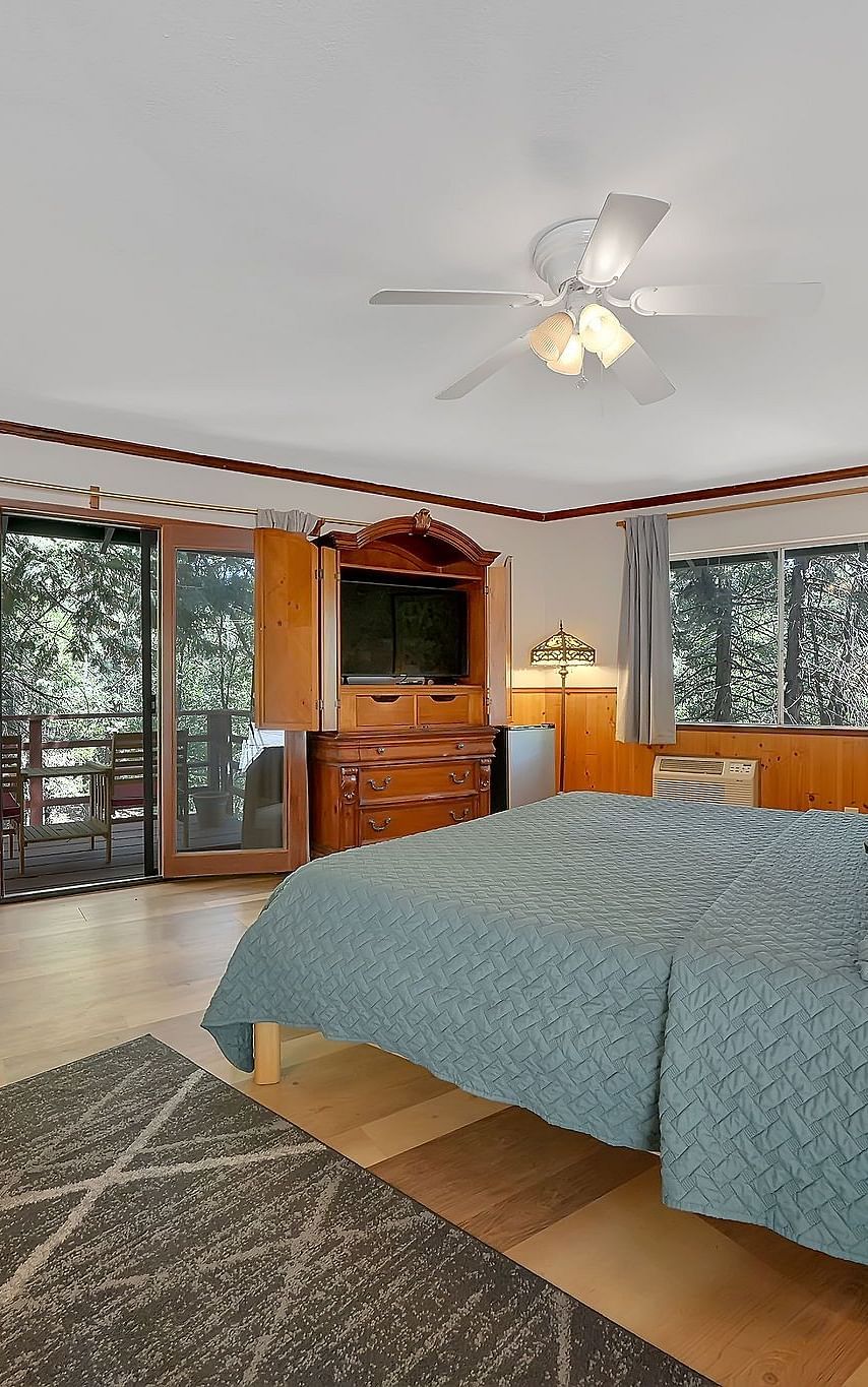 A room at Narrow Gauge Inn with a double bed and sliding doors opening up to a balcony with seating.