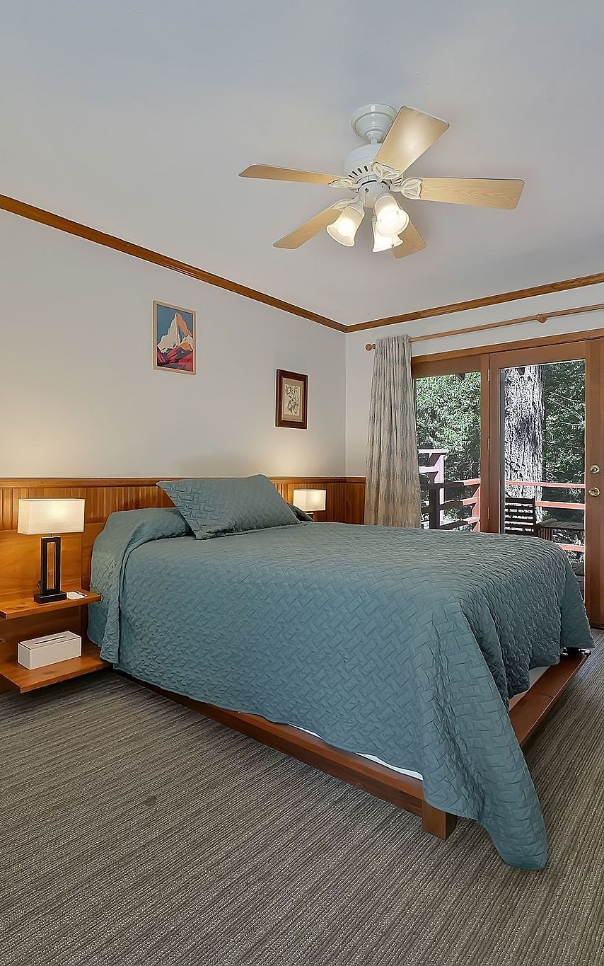 A view of a room at Narrow Gauge Inn with a double bed and sliding doors opening to a balcony.