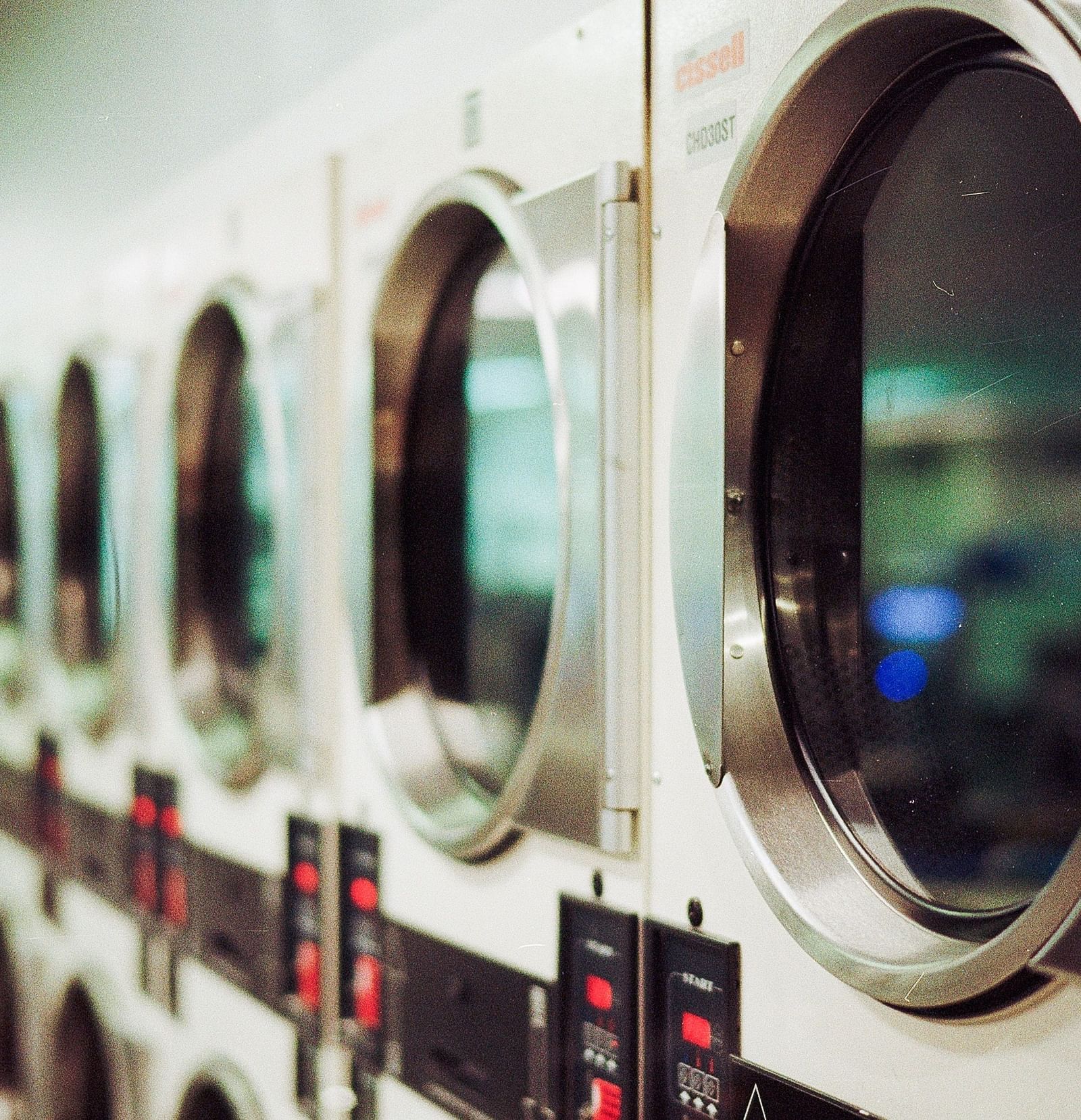 Many washing machines stacked next to each other inside a room