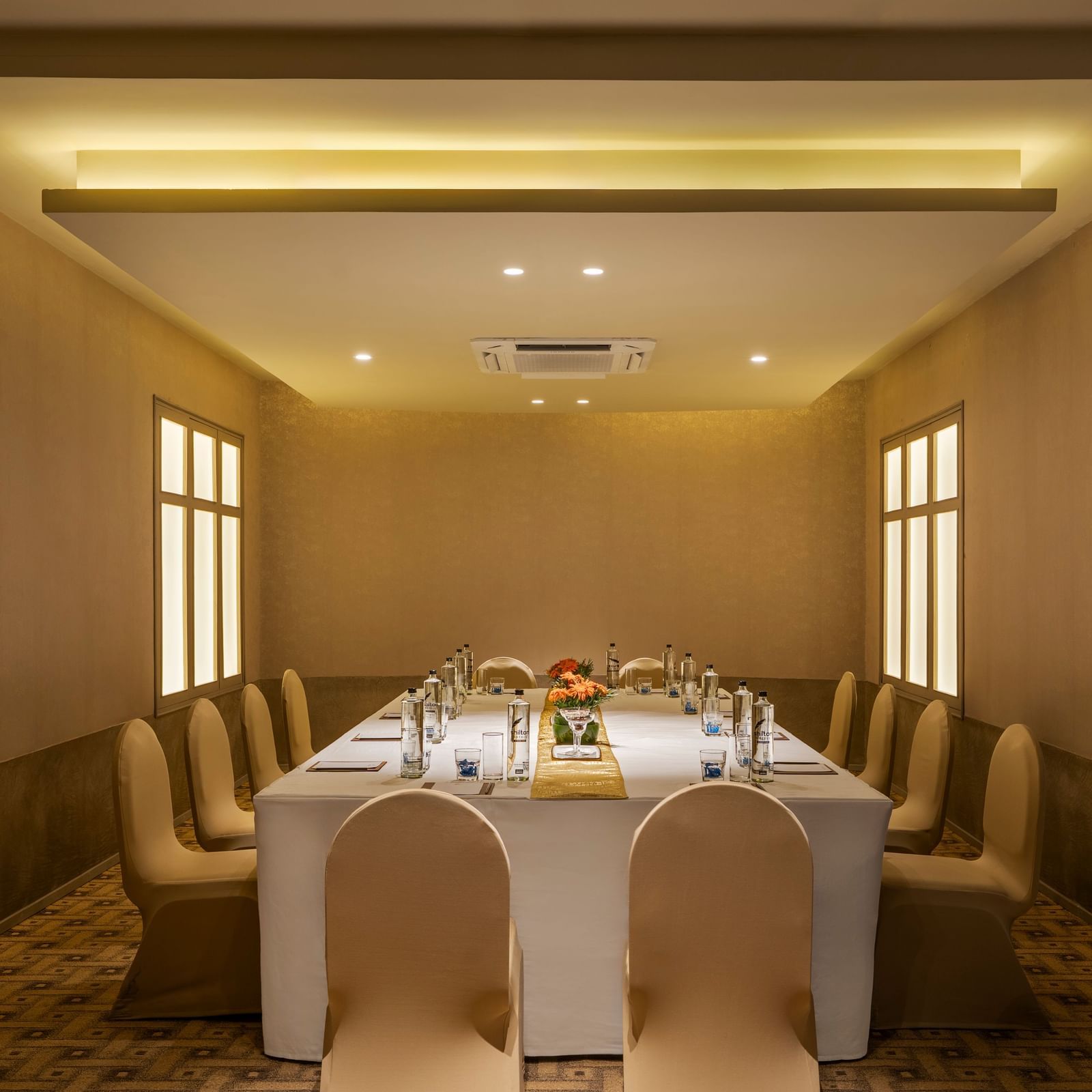  A meeting room at Shilton International, Kochi with a long table surrounded by chairs, set for a formal gathering.