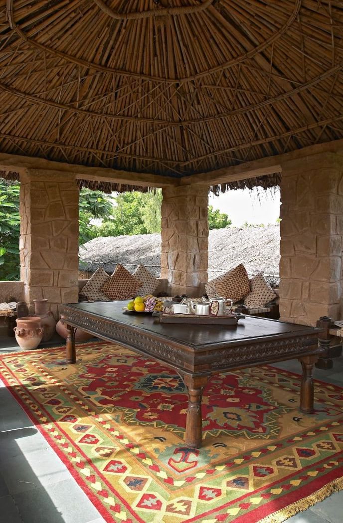 An image of the Taasli Restaurant at Manvar Shergarh with a wooden table laid out with crockery over viewing the landscape - Manvar Resort & Desert Camp