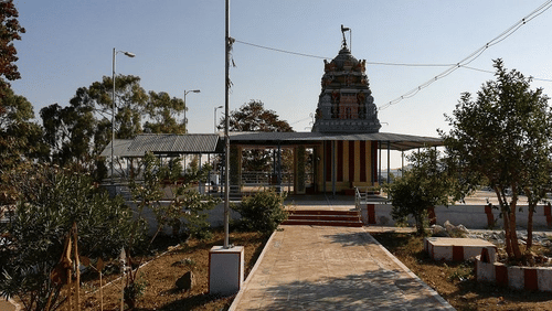 Temple with a tall gopuram, surrounded by trees and clear sky.