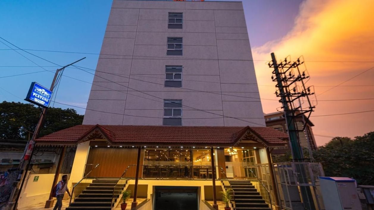 The facade of VITS Select, Bengaluru as seen from the front, featuring stairs leading up to the hotel with a vibrant sky in the background.