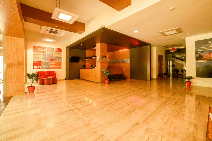 alt-text A spacious and modern hotel lobby with sleek wooden reception desk, warm ambient lighting, and informative wall posters showcasing local attractions.