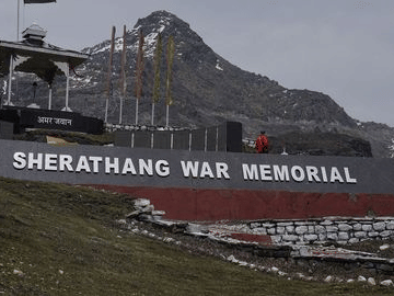 Sherathang War Memorial in Ladakh set against rugged mountains, honoring Indian soldiers with a stone monument and flags.