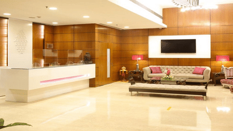 Spacious contemporary hotel lobby with a front reception desk and lounge seating area.