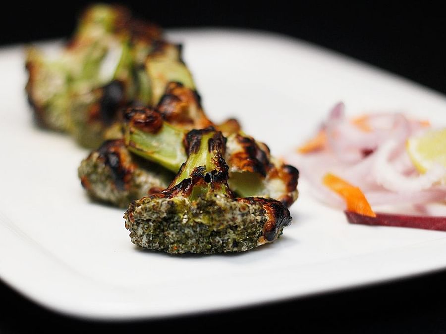 Cheesey Brocolli plated in a white dish with a side of onions