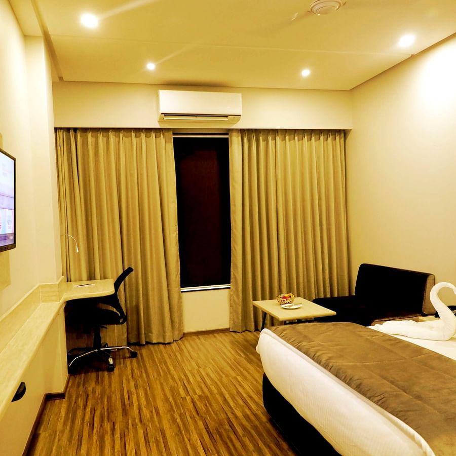 A sideview of a spacious room with a bed and a TV on the wall.