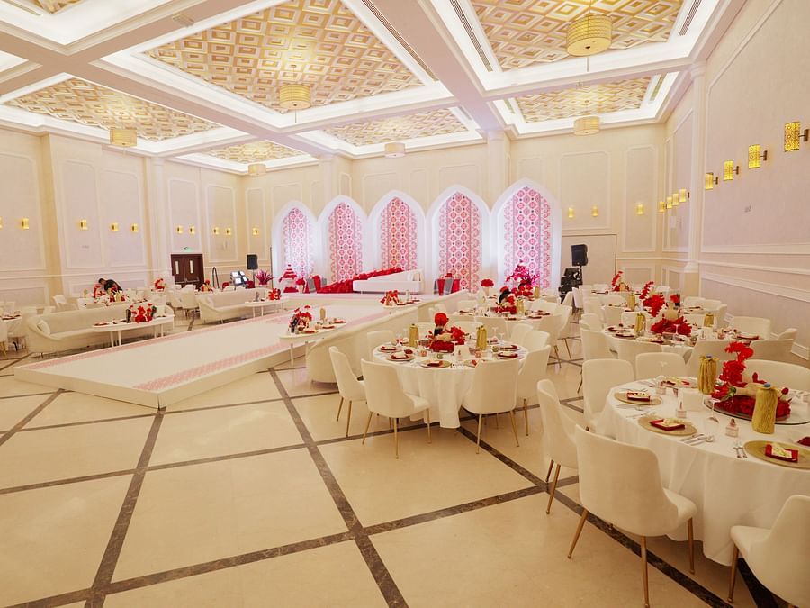 A corner view of an elegantly decorated banquet hall at La Maison, Doha, with round tables set for a formal event.