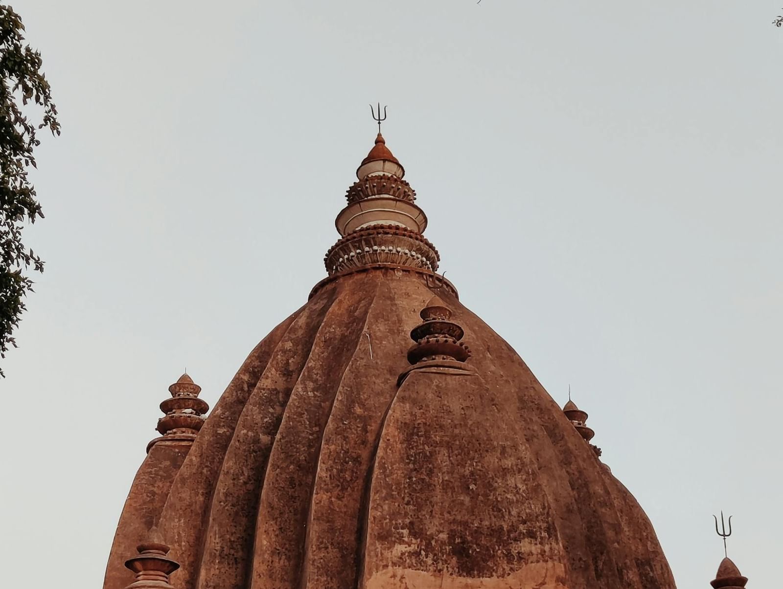 Ancient temple structure made of stone with trees surrounding the area and clear sky above.