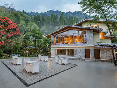 Facade of Summit Norling Resort & Spa, Gangtok with trees on the side and mountains in the background.