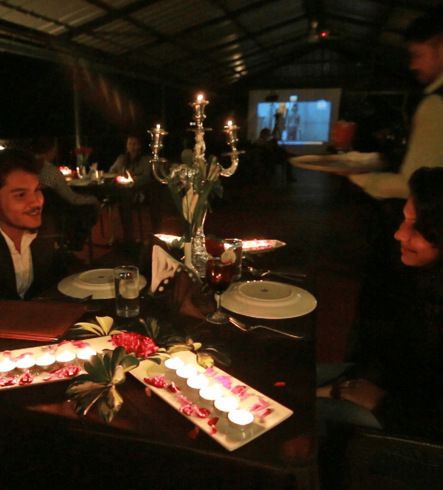 Image of a two people dining with tea light candles placed on the table at Coorg Jungle Camp Backwater Resort, Kushalnagar.