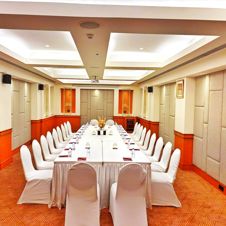 Banquet hall arranged in a U-shape seating setup with white chairs and table settings at The Residency Karur, suited for meetings and conferences