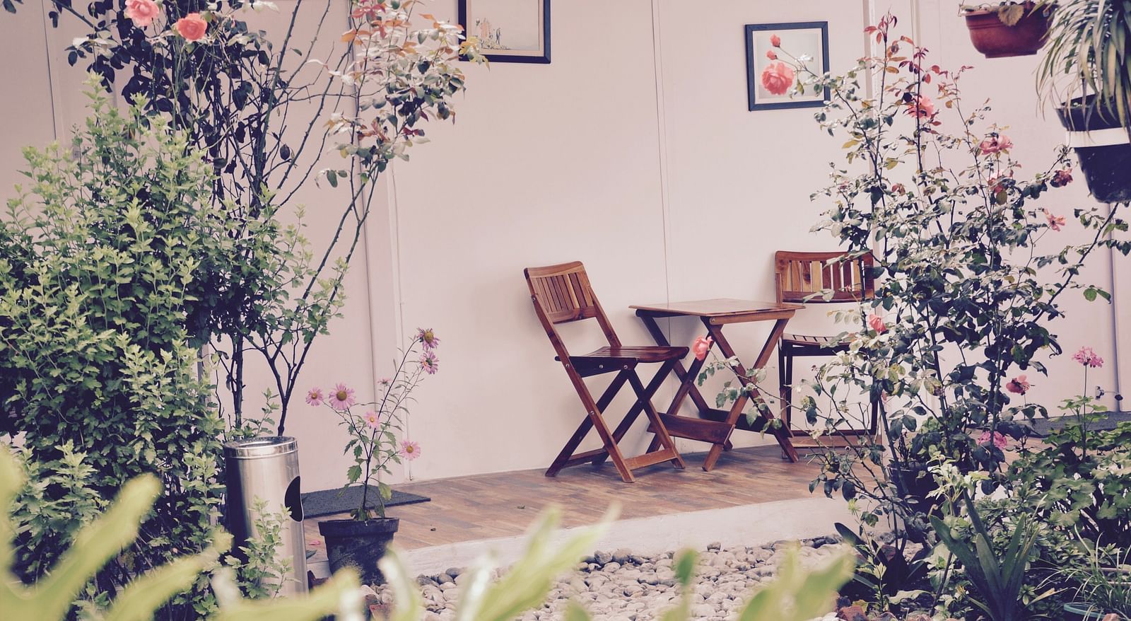 image of the beautiful outdoor porch of the deluxe room with a lot of floral plants with wooden folding chairs - The Tattva Boutique Resort