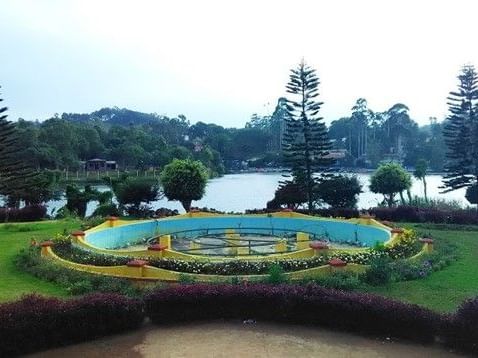 A beautiful wide-angle shot of Anna Park in Yercaud with an empty fountain pit in the centre surrounded with well-trimmed bushes.