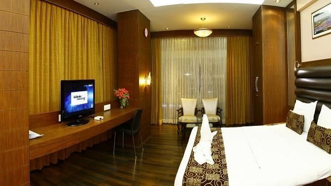 A king bed with cushioned headboard and a tv opposite the bed inside Premium Room at VITS Select Grand Inn Ratnagiri