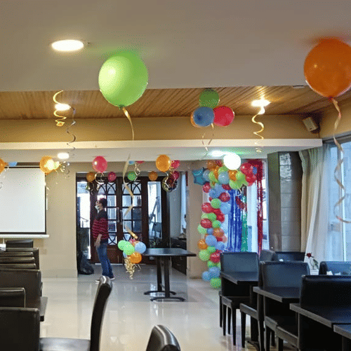 Room with festive balloon decorations and a projector setup at Central Hotels.