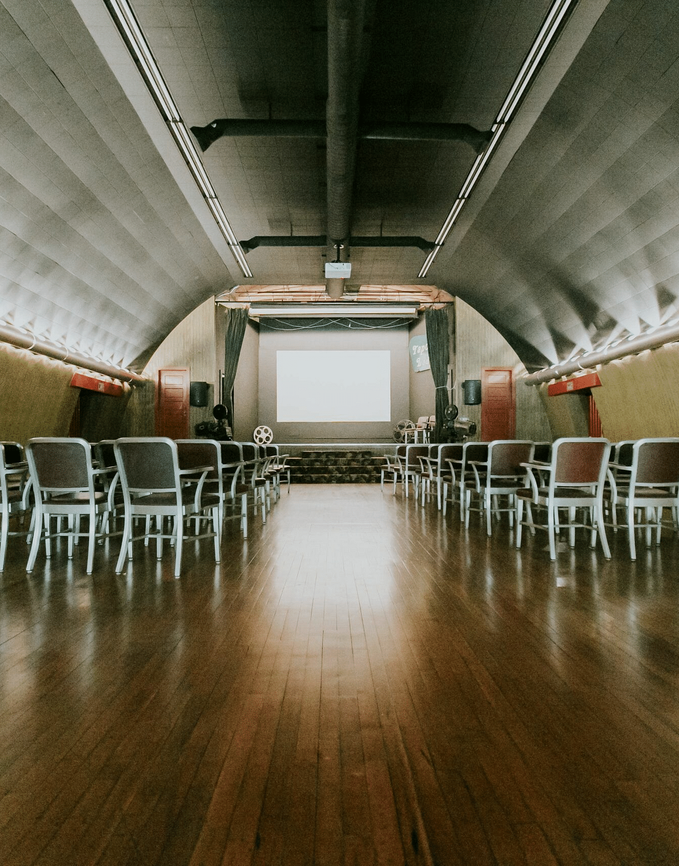 full view image of the expansive Tin Can Theater with a lot of chairs facing towards the stage - Historic Tapoco Lodge