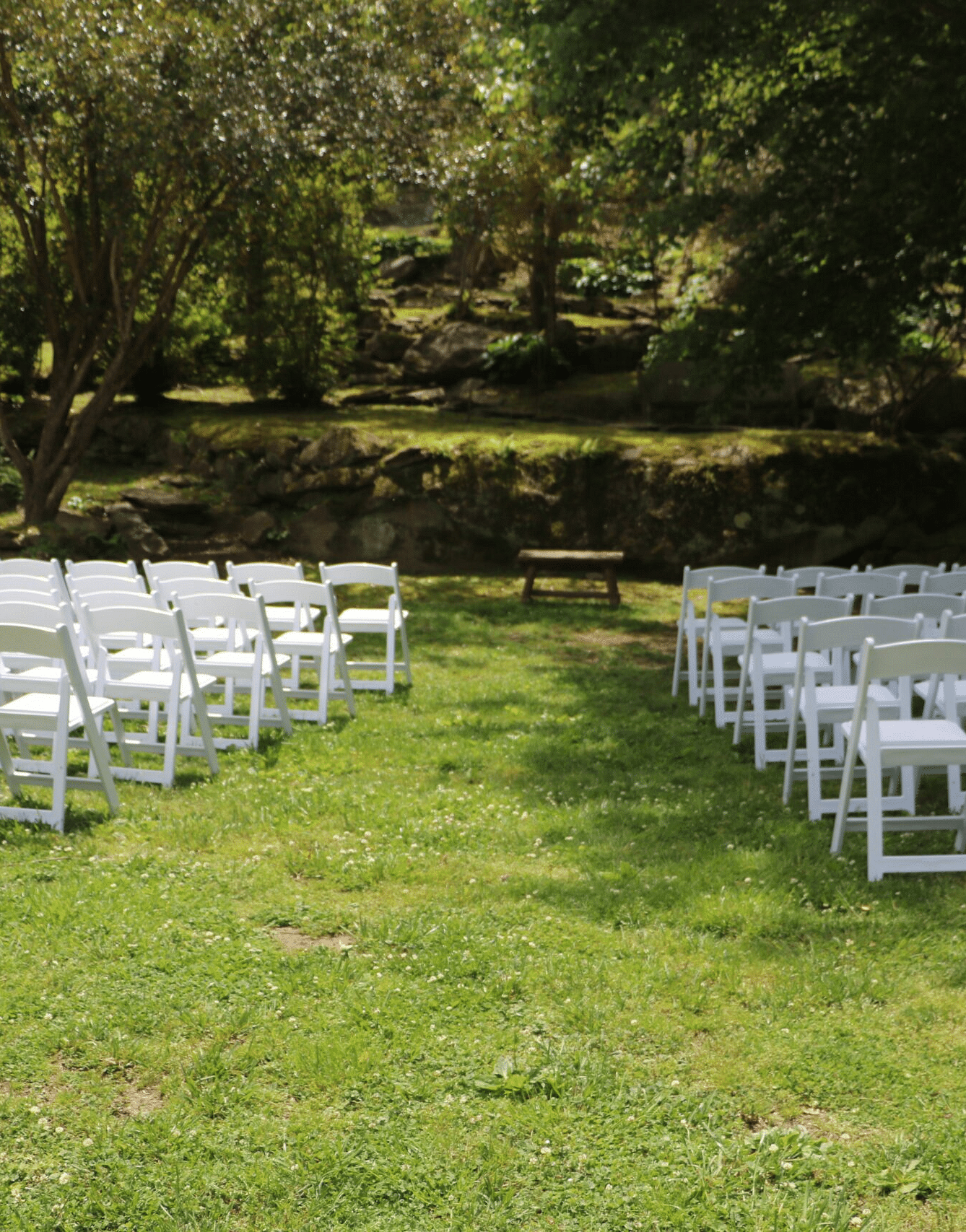 many white colored folding chairs set up in the Riverside Lawn for a wedding ceremony on a bright sunny day - Historic Tapoco Lodge