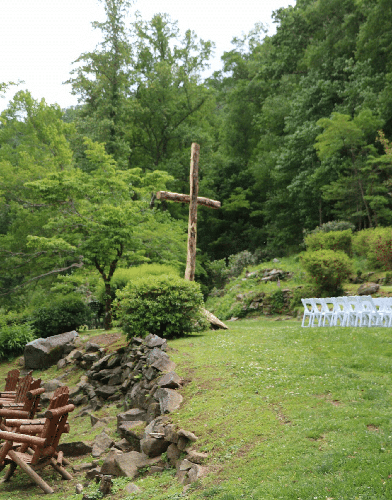 full view of the Riverside Lawn surrounded by tall towering trees with white chairs arranged in the lawn  - Historic Tapoco Lodge