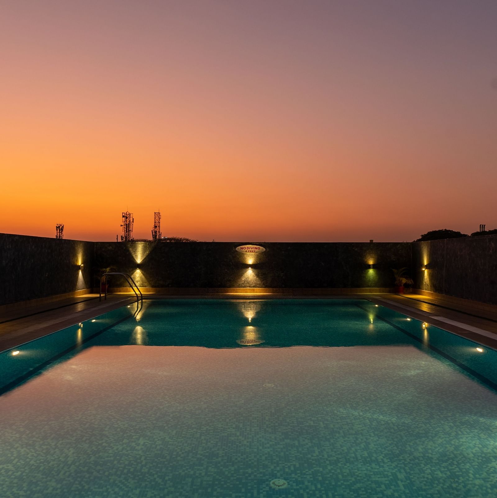 Overview of the swimming pool with the lights on and the evening sky after the sunset - Hotel Pai Vista, Mysore