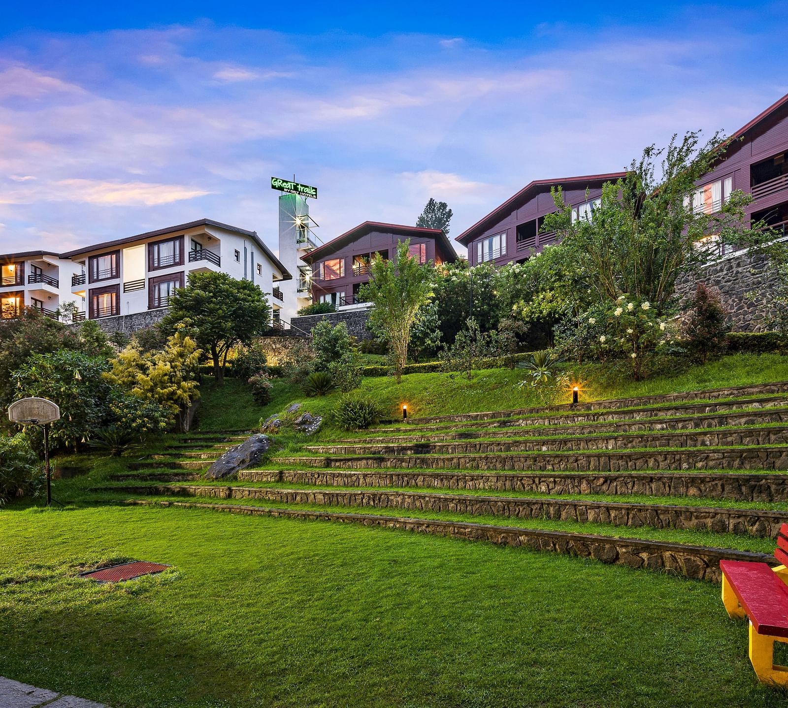 Exterior view of the hotel with lush greenery with the hotel buildings in the background - GReaT Trails Kodaikanal By GRT Hotels