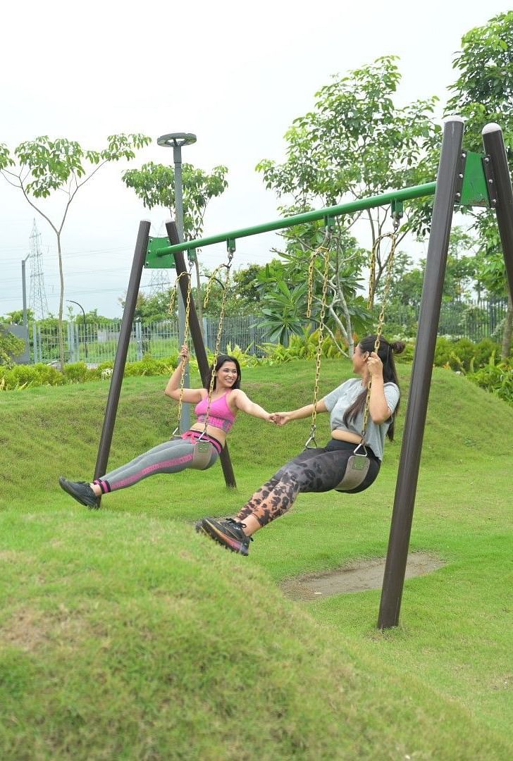 Two women sitting on swings in the garden area of Singalila Club