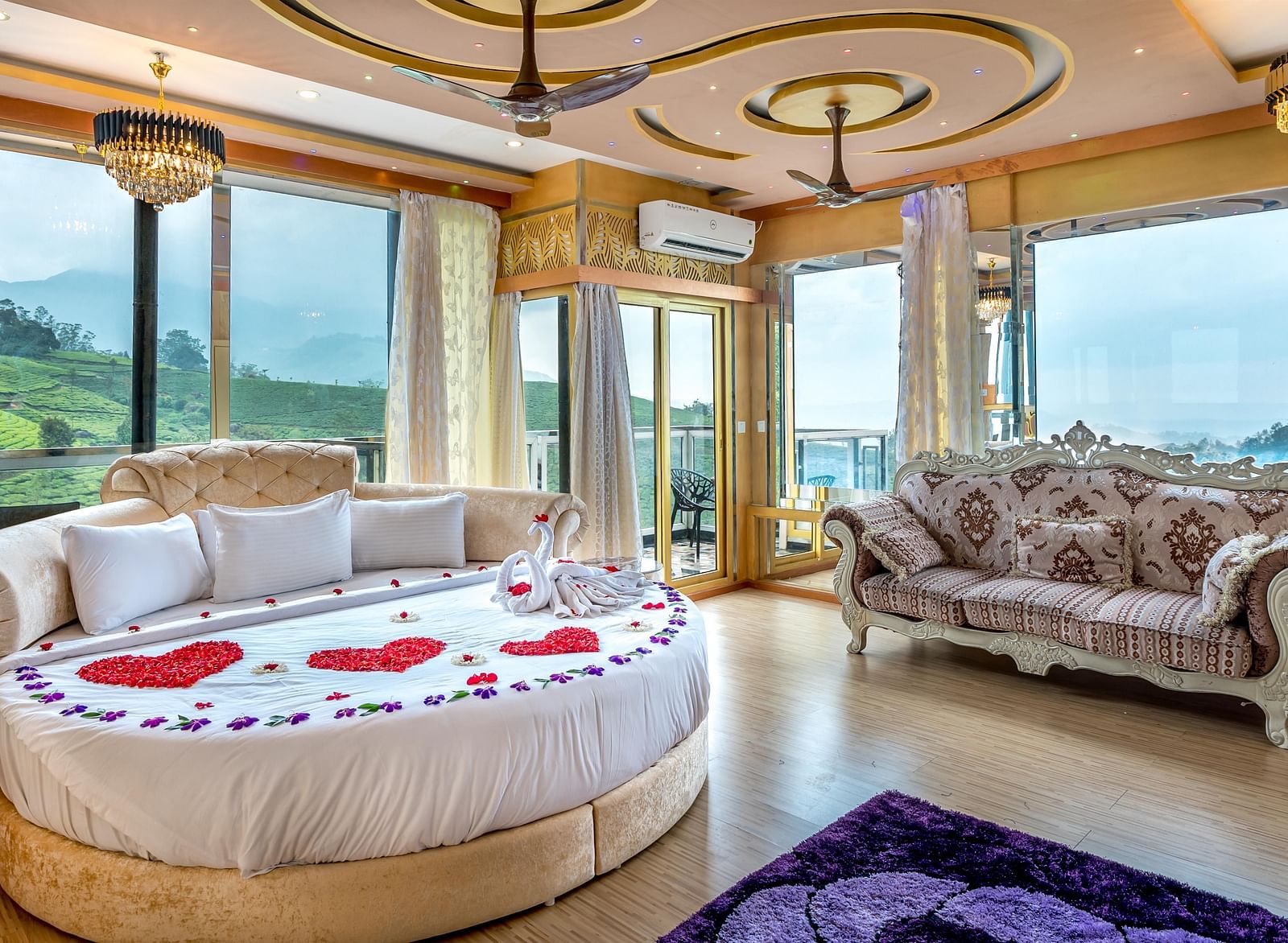An image of a bedroom with round bed with cushions and next to it is a stylish sofa and the entire room is filled with natural light -  Parakkat hotel & resorts