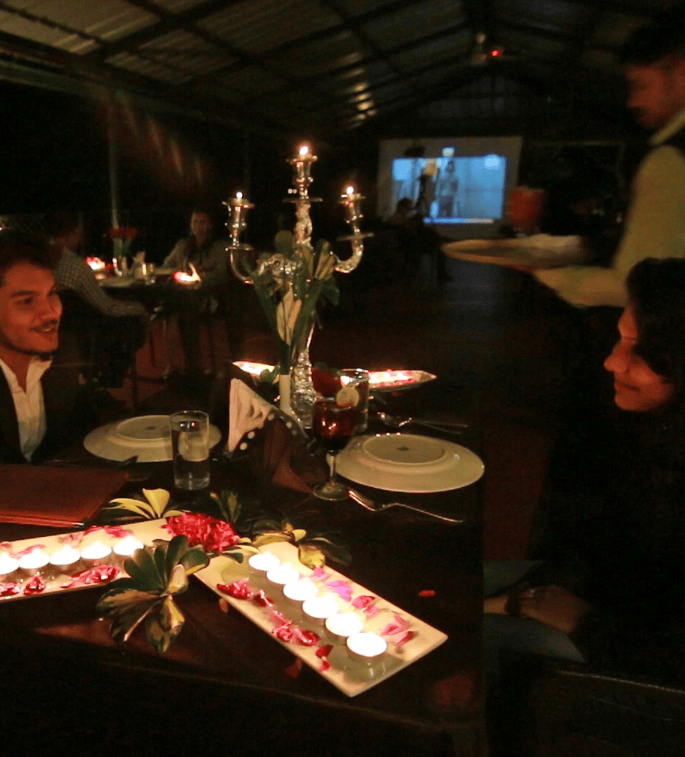 Image of two people dining with tea light candles placed on the table at Coorg Jungle Camp Backwater Resort, Kushalnagar.